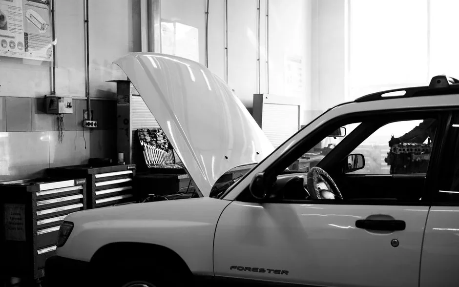 Voiture familiale capot ouvert dans un atelier de garage, entre servantes à outils et établi